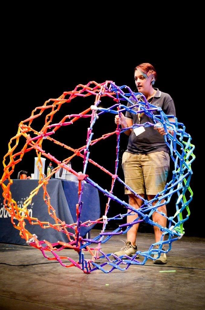 A person holding a expanded 4ft ball called a Hoberman Sphere